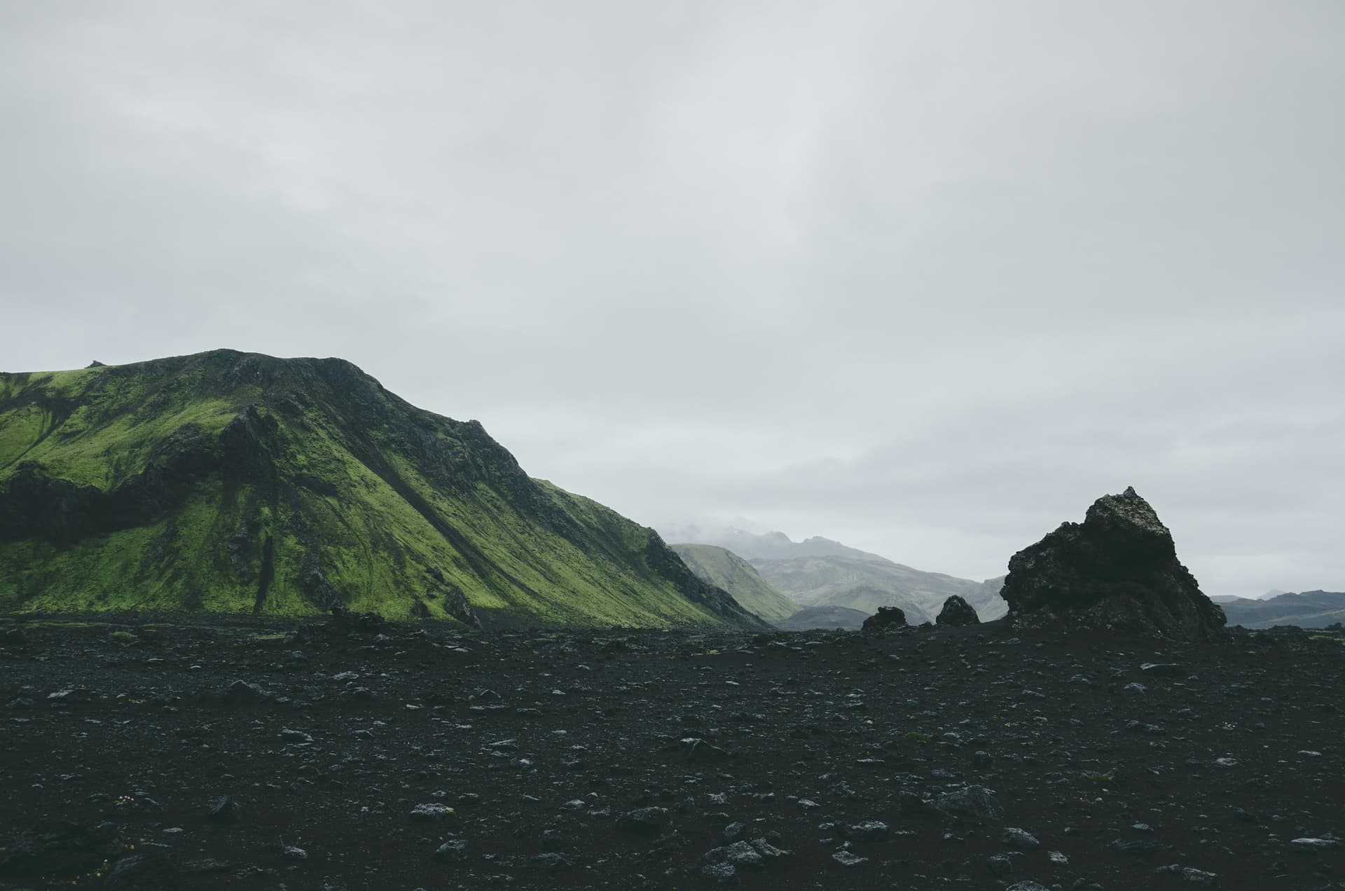Moss-green mountain over a black lava field in Iceland